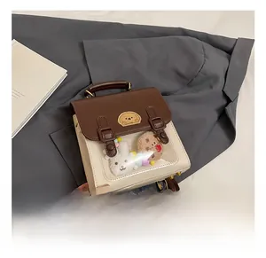 Detail of a two-tone ita bag with transparent PVC window and mini plush toy decorations