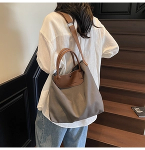 Close-up of gray canvas tote bag with brown leather handles and adjustable shoulder strap