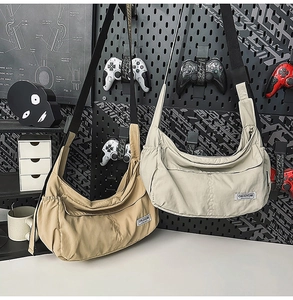 Detail of khaki and gray nylon messenger bags with adjustable straps on pegboard