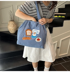 Detail of blue and white checkered canvas tote bag with cute cartoon bread embroidery