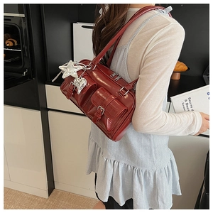 Detail der tiefroten Schultertasche mit Multi-Taschen und Stern-Herz-Metallanhängern