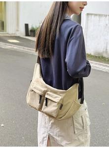 Detail view of khaki nylon crossbody bag with dual front flap pockets and high-capacity design