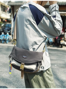 Detail shot of the nylon crossbody bag showing the buckle closure and woven pendant