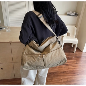 Detail of khaki nylon messenger bag with double zipper pockets and wide strap