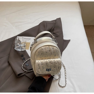Close-up of beige quilted backpack featuring sparkling rhinestones and silver chain straps