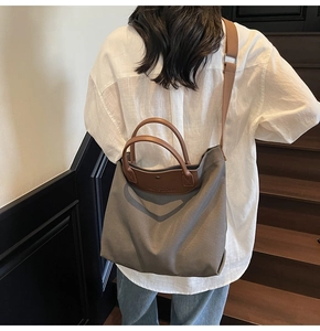Detail of grey canvas tote bag featuring brown leather handles and adjustable shoulder strap