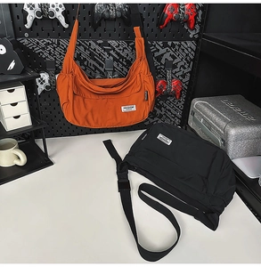 Detail of nylon messenger bags in orange and black with pockets and woven straps