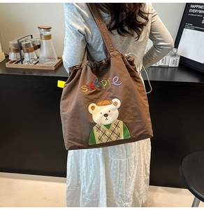 Detail of cute embroidered bear and steppe text on brown canvas drawstring tote bag