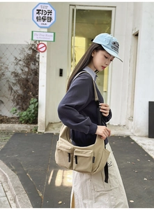 Detail of khaki nylon dumpling bag showing dual front pockets and durable canvas texture