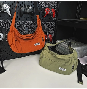 Detail view of nylon crescent bags in orange and green on a tech-style backdrop