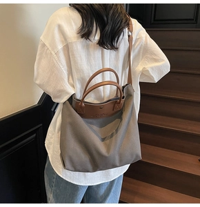 Detail view of large canvas tote bag showing genuine leather handle and shoulder strap