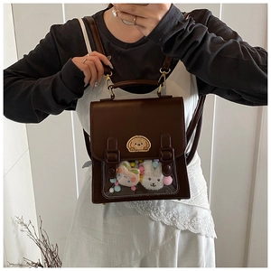 Detail view of a vintage dark brown leather itabag with transparent window and plush charms