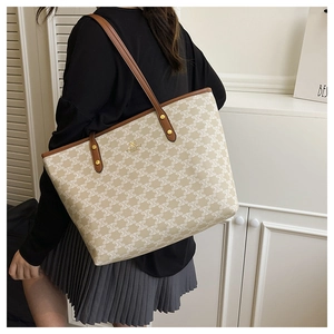 Detail of a large monogram tote bag with brown leather straps shown on a model side-view