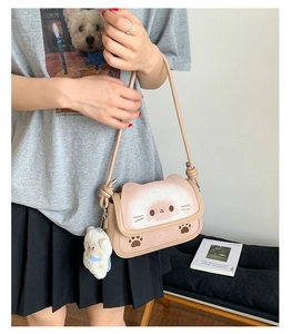 Dettaglio borsa beige a forma di gatto con impronte di zampe e ciondolo di peluche