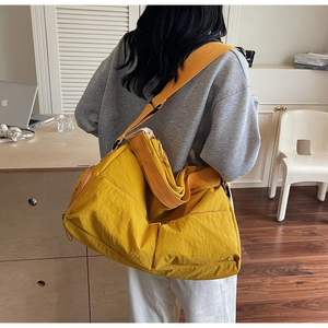 Close-up of bright yellow nylon tote bag with wide shoulder strap and spacious side pocket