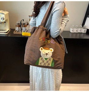 Detail of cute bear embroidery and drawstring closure on brown canvas tote bag