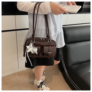Detail der dunkelbraunen Lackleder-Handtasche mit silbernen Sternanhängern und Schnallentaschen