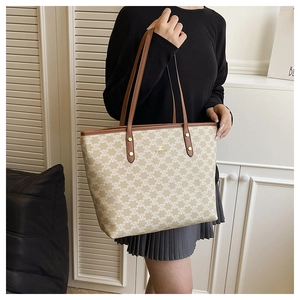 Close-up of leather handles and gold metal logo on a vintage patterned tote bag