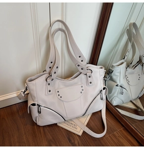 Détail du sac cabas crème en cuir avec rivets en étoile et plusieurs poches zippées