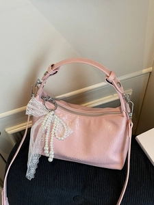 Sac à main en cuir verni rose avec nœud en dentelle et breloque en perle sur siège