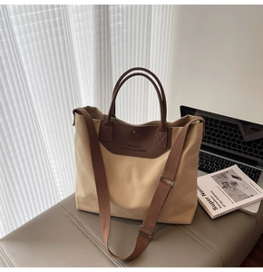 Detailed view of canvas tote bag with brown leather patches and adjustable shoulder strap