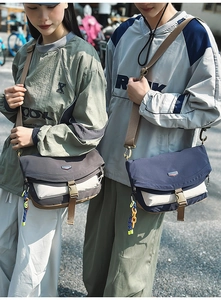 Outdoor lifestyle shot of two nylon crossbody messenger bags with buckle flap and strap detail