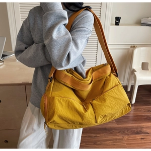 Detail of a bright yellow nylon tote bag featuring multiple pockets and a wide strap