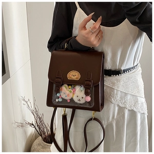 Detail of dark brown leather ita bag with clear window showing plush toys and charms