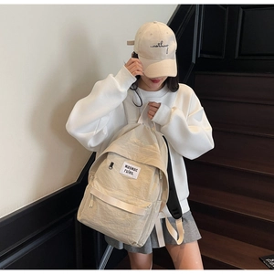 Dettaglio dello zaino in nylon color crema con logo quadrato su una scala urbana moderna