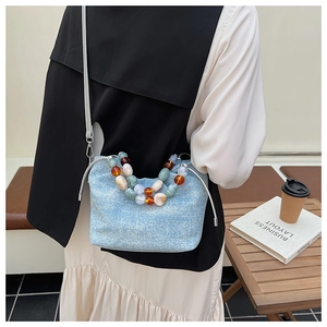 Detail of light blue pleated bucket bag with decorative marble pattern beads and long strap