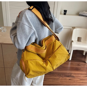 Detail of yellow nylon tote bag with multi-pocket design and adjustable strap
