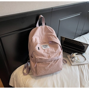 Dettaglio dello zaino casual rosa chiaro con tessuto stropicciato e toppa bianca