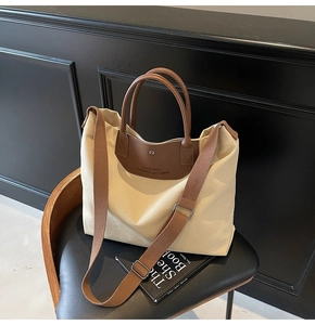 Detailed macro view of the beige canvas tote bag with embossed leather logo and fabric strap