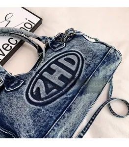 Dettaglio della borsa tote in denim blu con grande ricamo ZHD e manico superiore