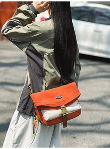 Detail of outdoor crossbody bag with orange flap, buckle closure and fabric texture