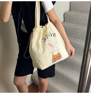 Close-up of cute rabbit embroidery on a cream canvas tote bag with drawstring closure