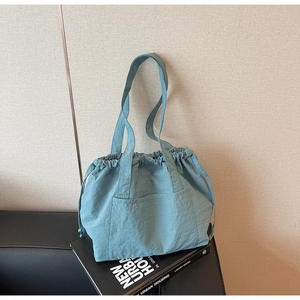 Close-up of light blue nylon tote bag featuring drawstring closure and front pocket