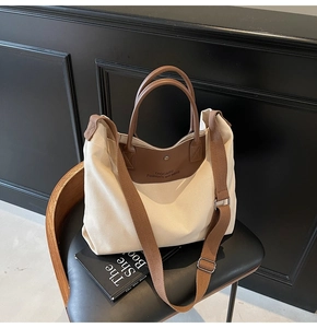 Close-up of beige canvas tote bag with brown leather trim on a vintage wooden chair