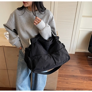 Detail of a black large-capacity nylon crossbody bag with multi-pocket design on the front