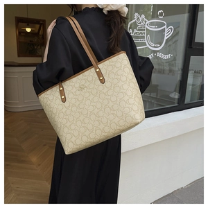 Detail of monogram tote bag with brown leather straps and gold rivet accents