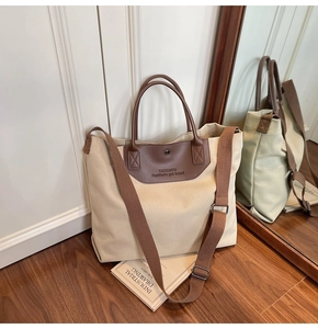 Detail of canvas tote bag showing dark brown leather straps and adjustable wide strap
