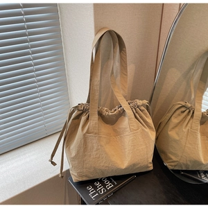 Detailed view of khaki nylon tote bag with drawstring closure and outer pocket