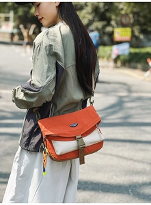 Detail of a waterproof nylon messenger bag featuring orange and beige color blocking