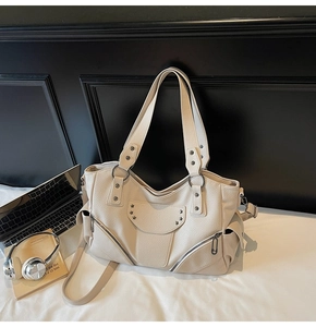 Détail du sac cabas blanc cassé avec rivets en étoile, cuir grainé et fermetures éclair en métal