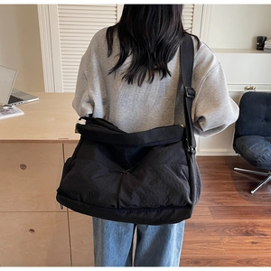 Close-up of black crossbody bag made from wrinkled nylon fabric worn by a female model