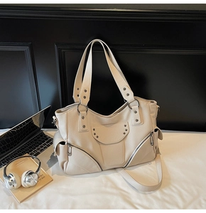Détail du sac en cuir crème avec clous argentés et design fonctionnel à poches multiples