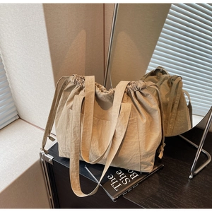 Detail of khaki drawstring tote bag featuring nylon fabric texture and front pocket