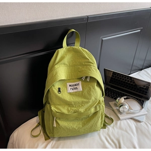 Dettaglio dello zaino in nylon verde lime con patch logo bianco e ampia tasca laterale