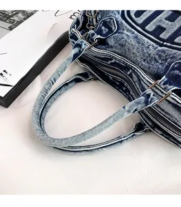 Dettaglio della borsa tote in denim blu con manici cilindrici e anello a D in metallo