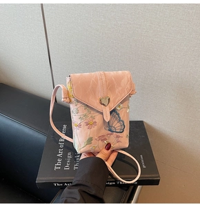 Gros plan sur le sac de téléphone en dentelle rose avec broderie florale et boucle cœur